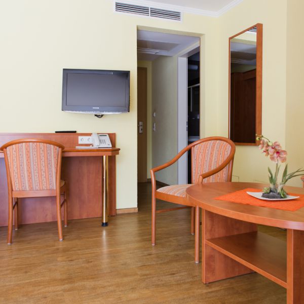 Die Doppelzimmer Comfort bieten etwas mehr Raum und einen Balkon. Auf diesem Bild ist die Einrichtung der Zimmer mit Sitzecke, Schreibtisch und Fernseher zu sehen.
